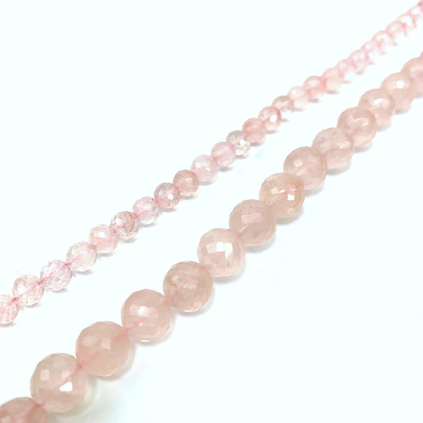 both strands of rose quartz beads ( left small, right large) on a white background