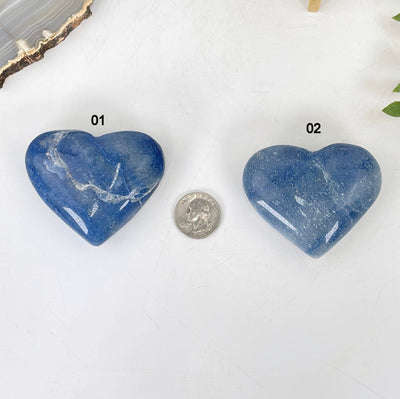 both blue calcite heart options laying flat with quarter for size reference