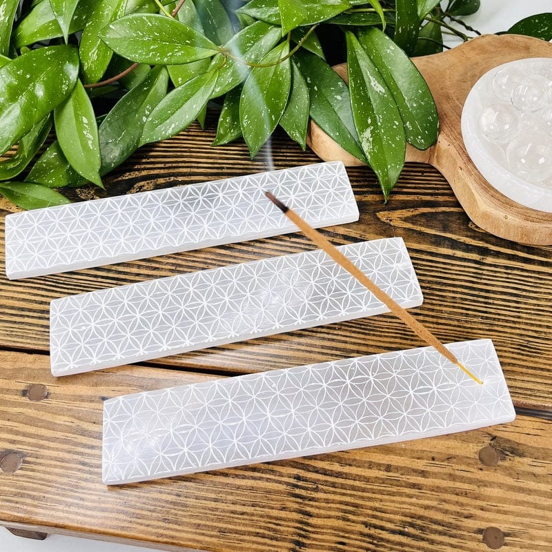 selenite bars with engraved flower of life grids on them displayed as home decor 