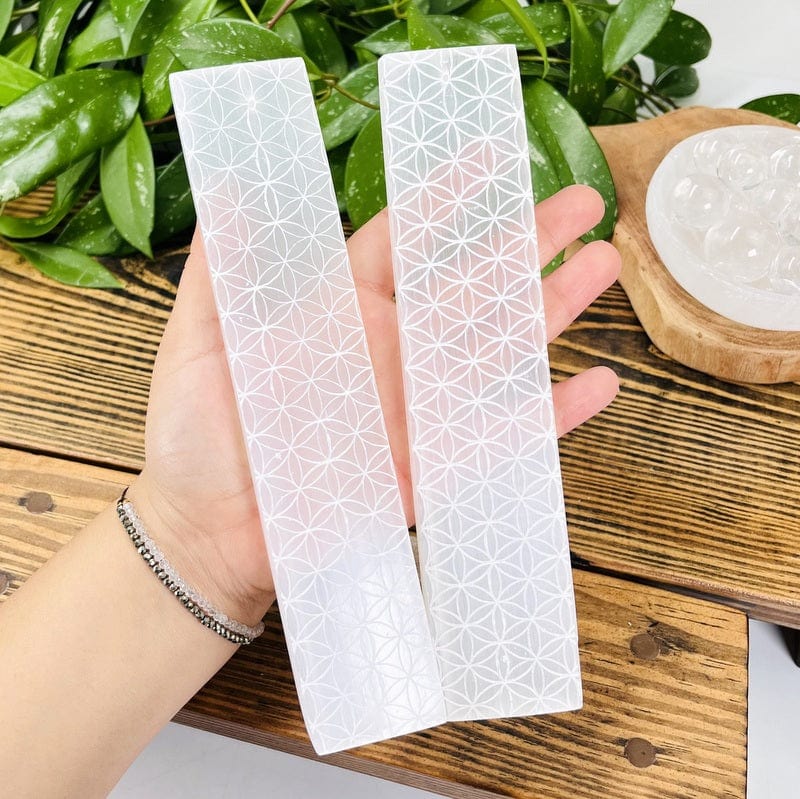 selenite bars with engraved flower of life grids in hand for size reference 