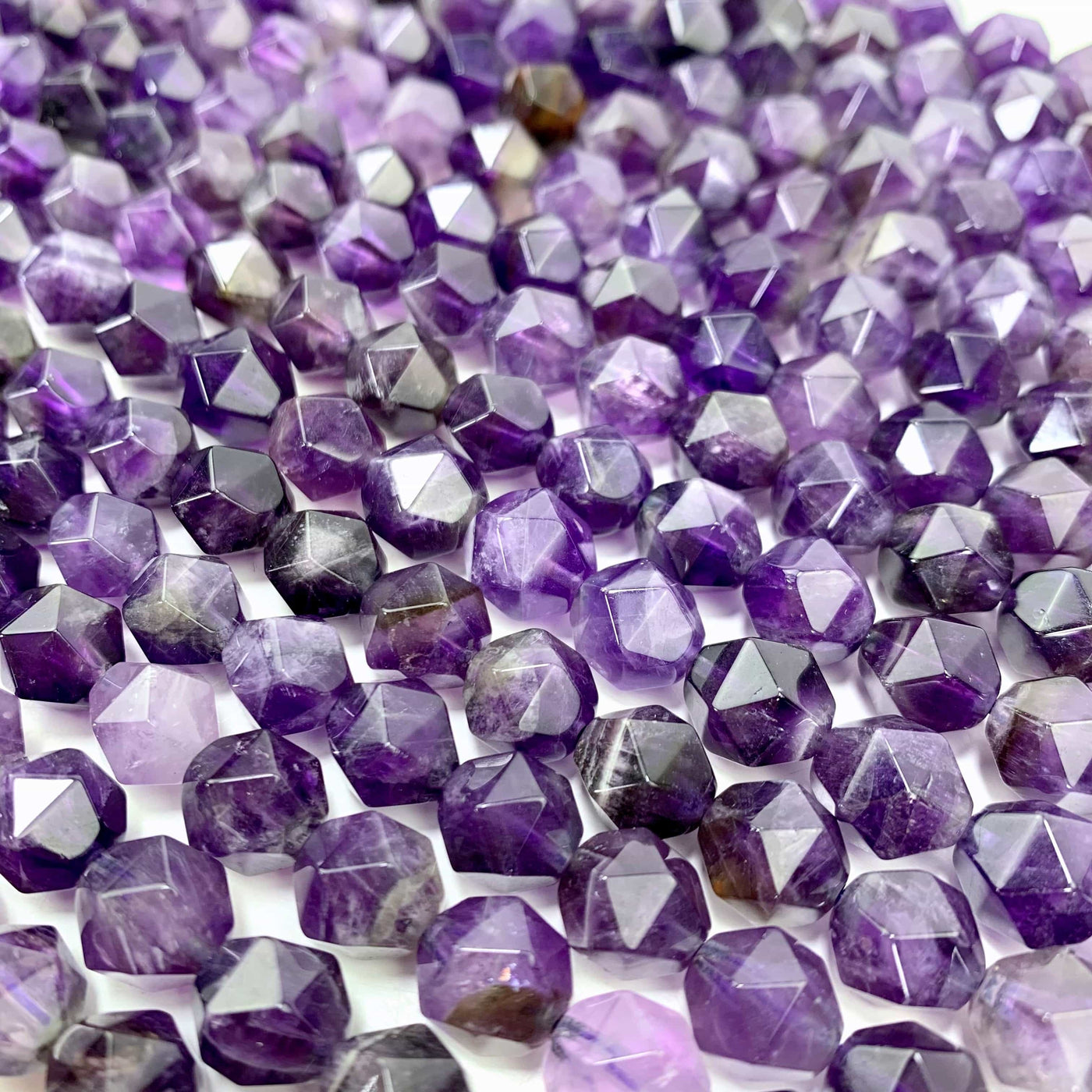 side close up angle amethyst faceted beads laid out on a white background