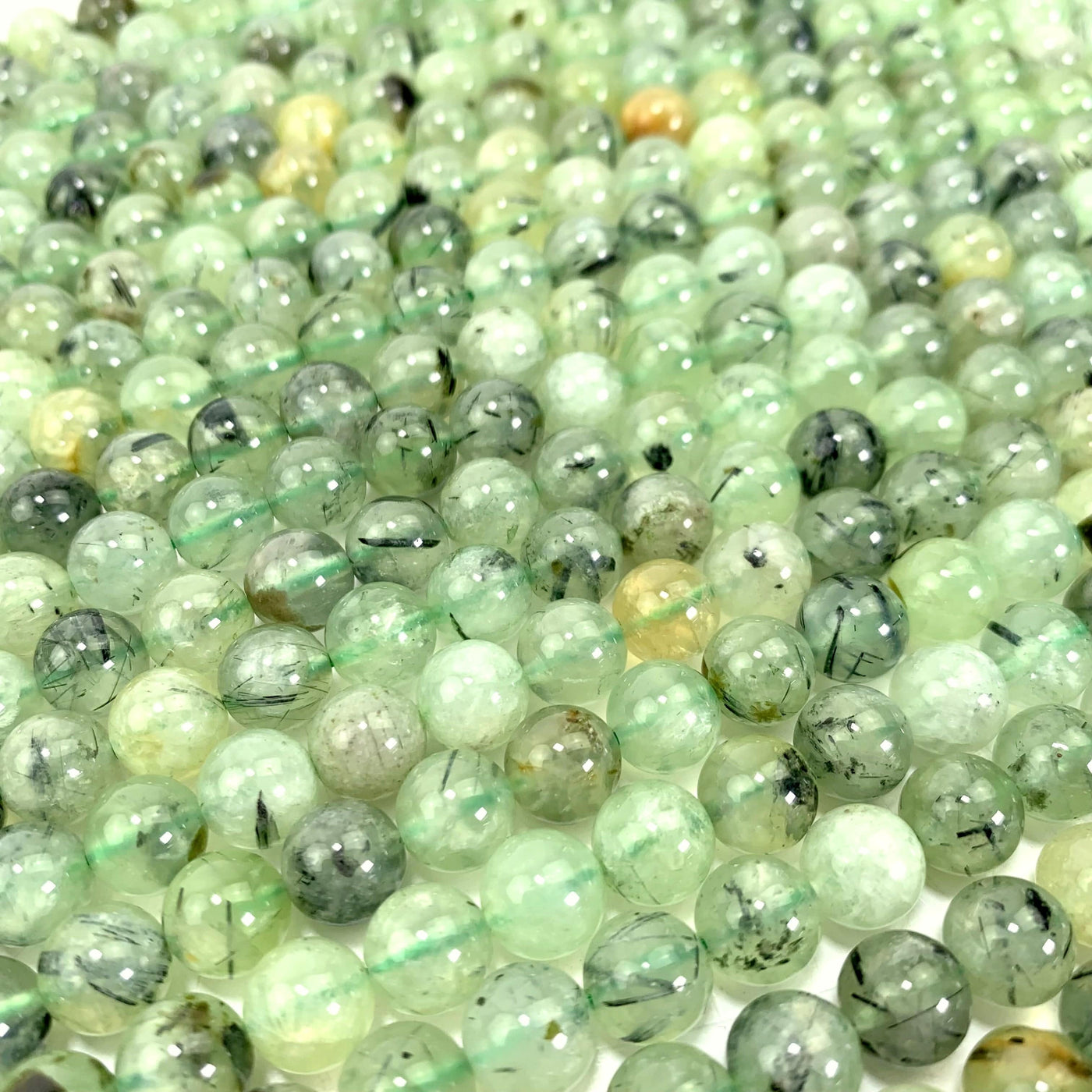 prehnite beads laid out on a white background