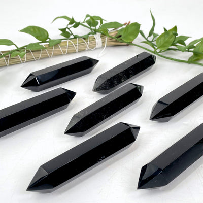 black obsidian double terminated points laying flat in front of bacldrop