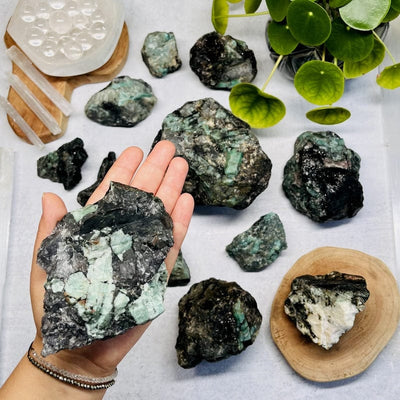 raw natural emerald cluster in hand for size reference 