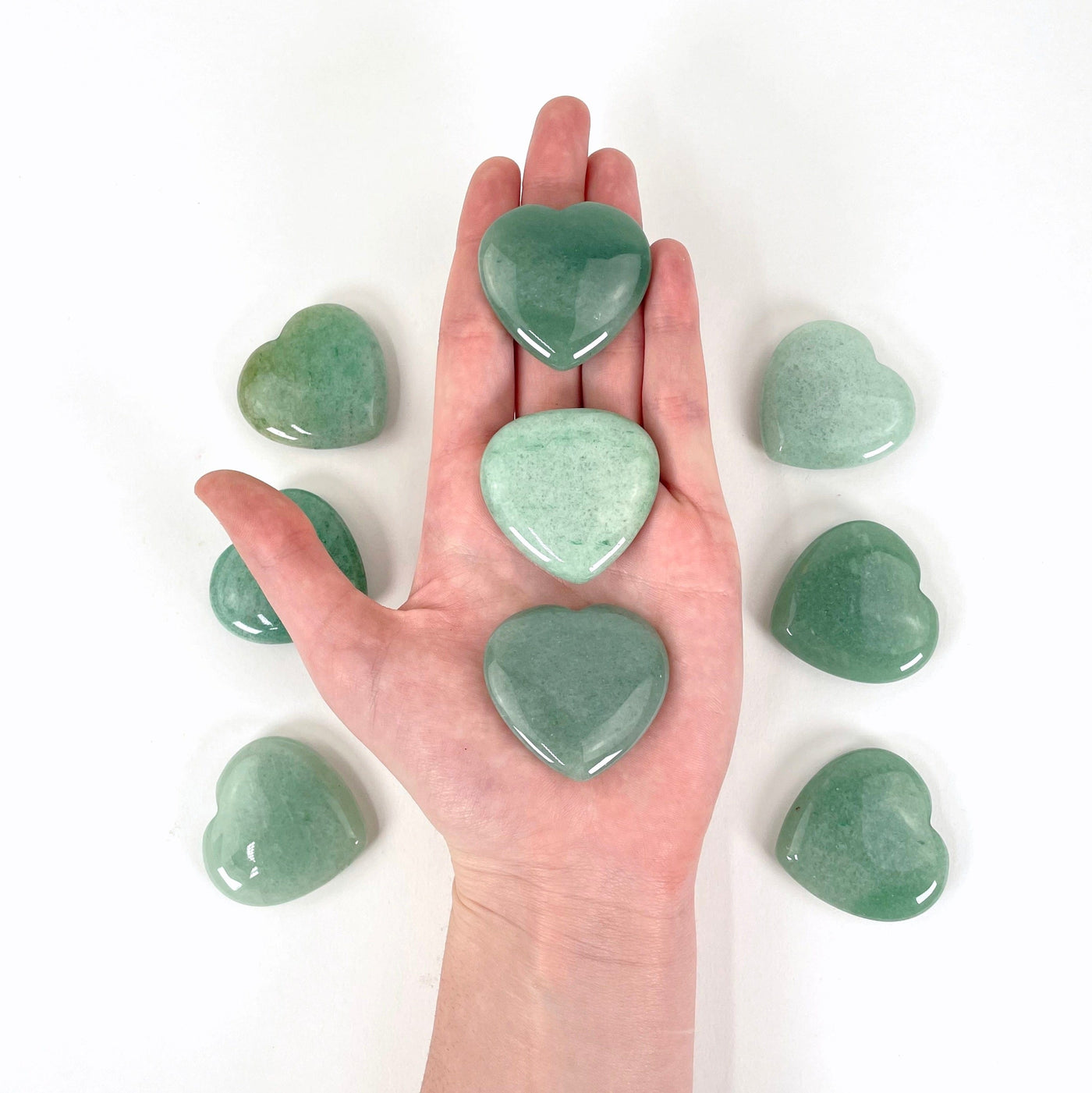 three green aventurine polished hearts in hand for size reference
