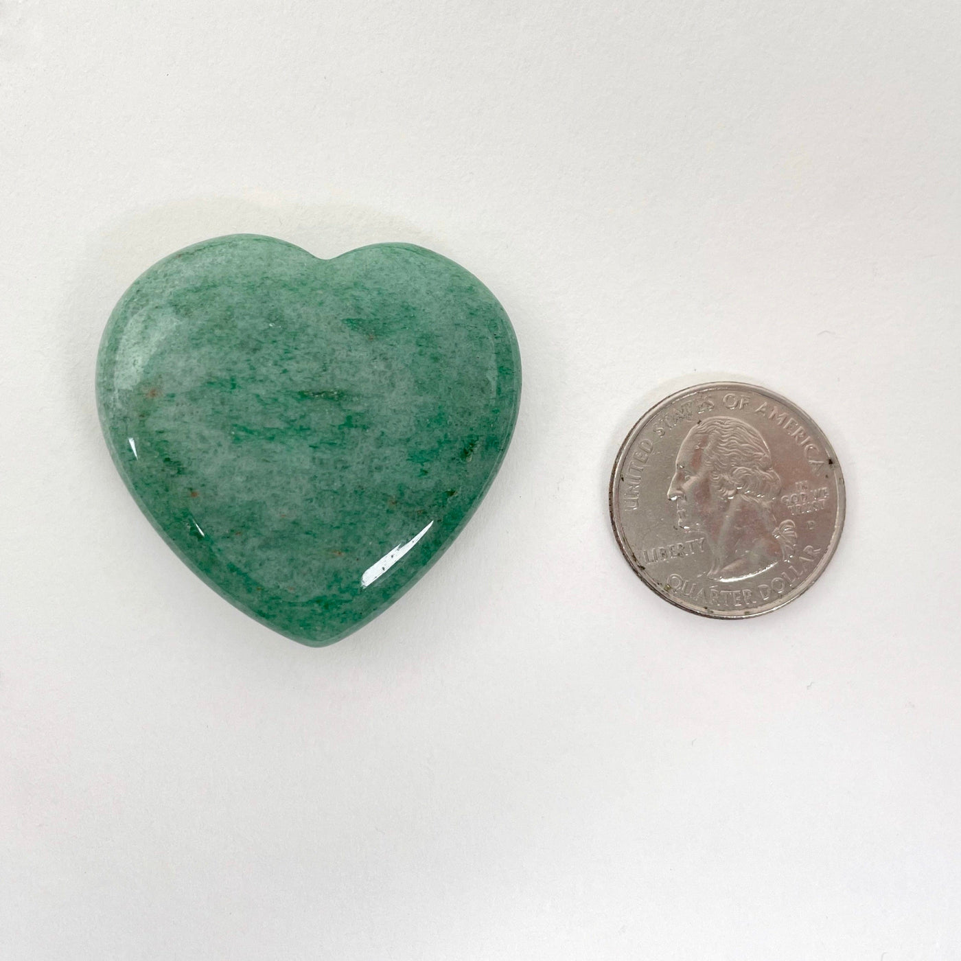 close up of green aventurine polished heart with quarter for size reference