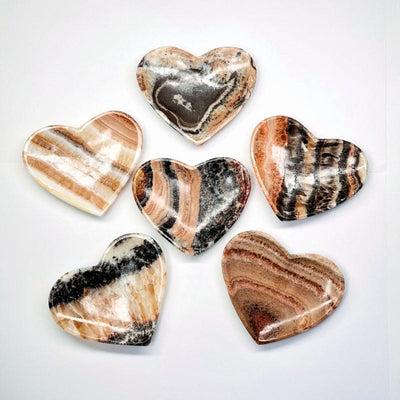multiple multi-colored mexican onyx heart bowls displayed to how the differences in the colors shades and patterns 
