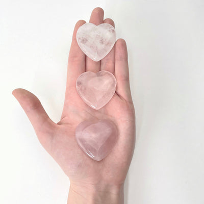 rose quartz polished hearts in hand for size reference and possible damages
