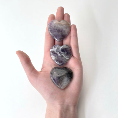 amethyst polished hearts in hand for size reference and possible damages
