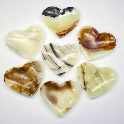 multiple green mexican onyx heart bowls displayed to show the differences in the color patterns 