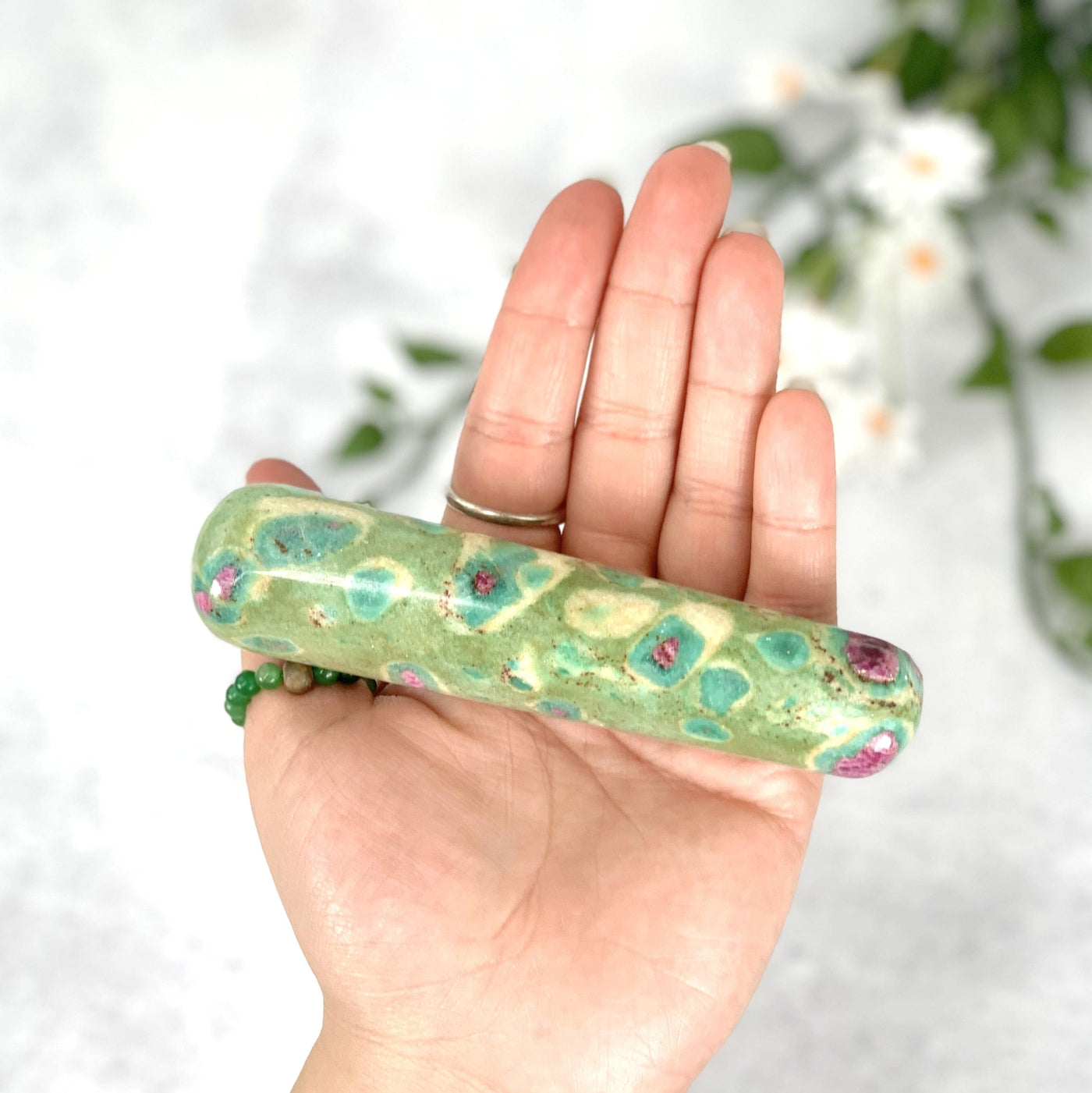 Hand holding up the Ruby fuchsite massage wand 