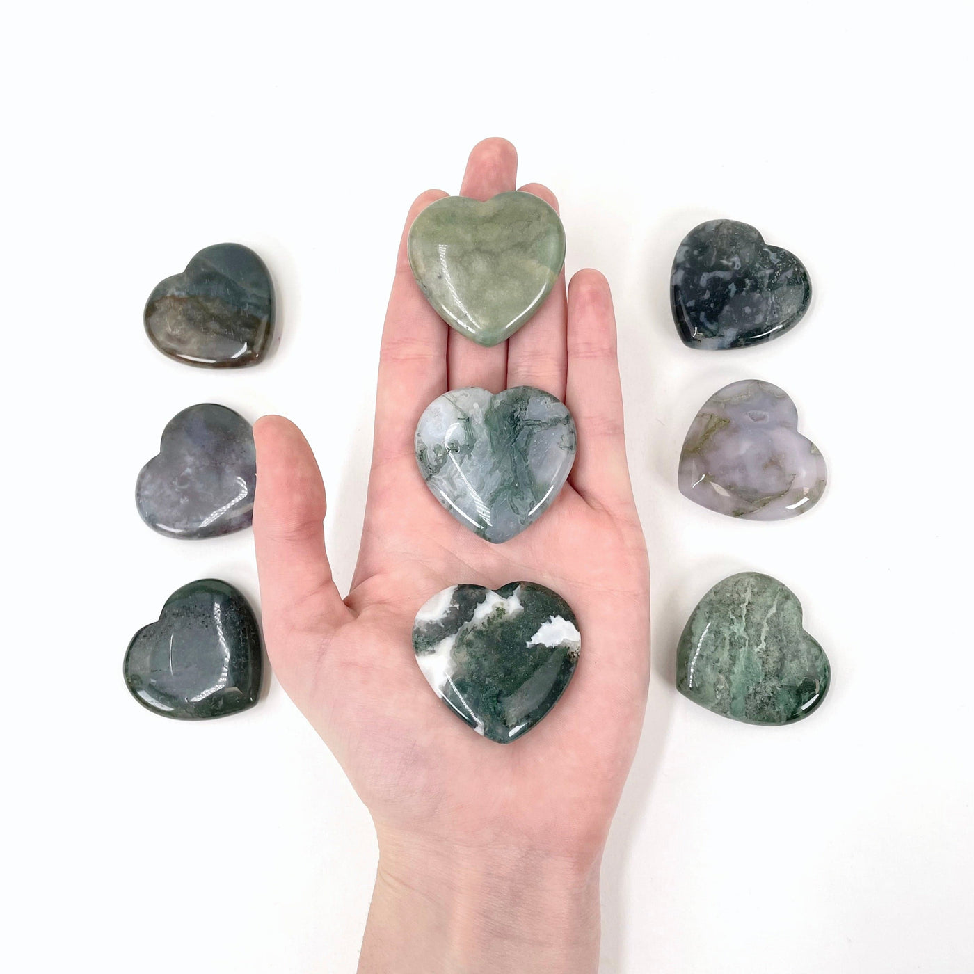 moss agate polished hearts in hand for size reference
