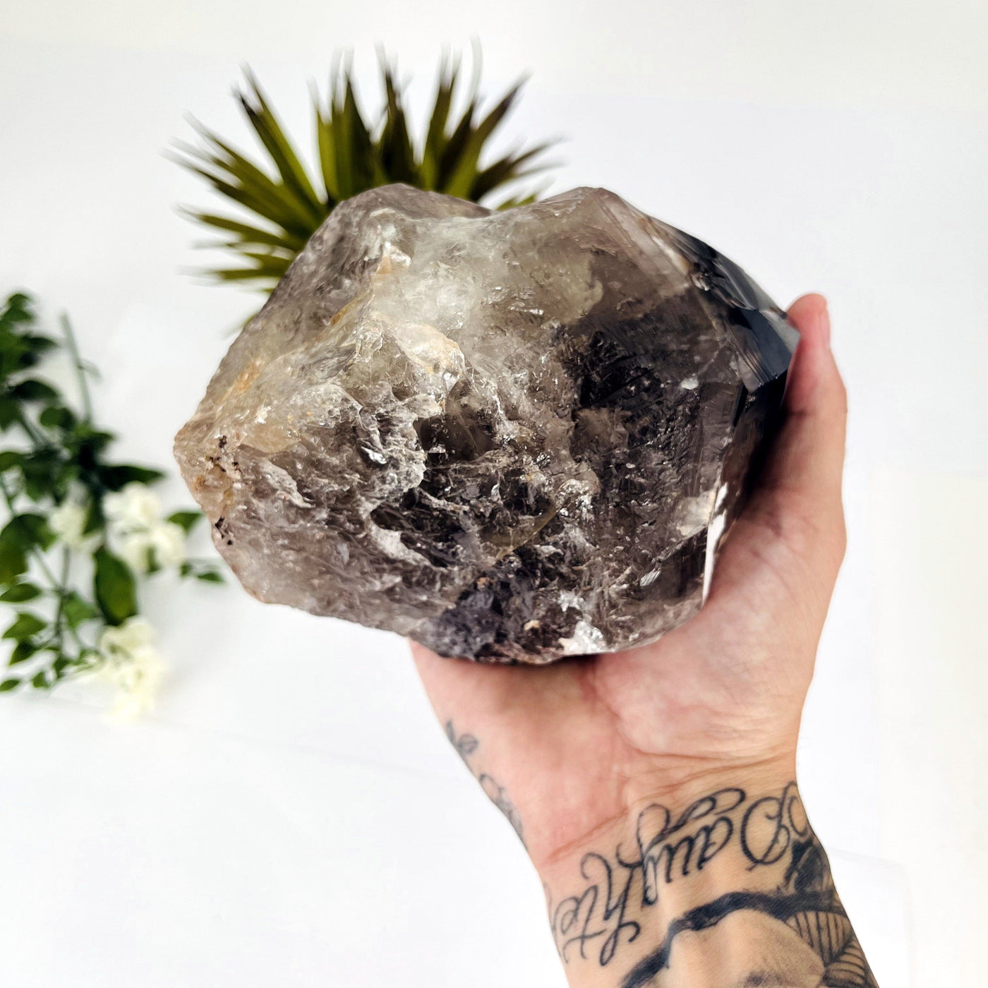 Picture of Side angle of smokey quartz point in a man's hand on a white background