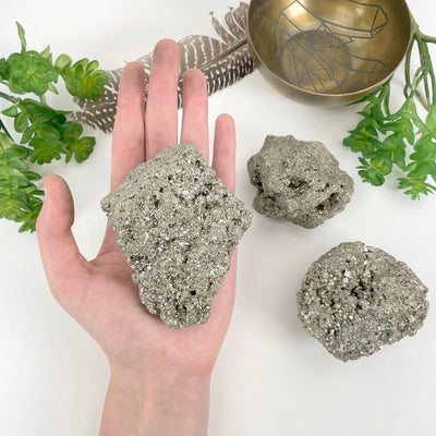rough pyrite stone in hand with backdrop for approximate size reference