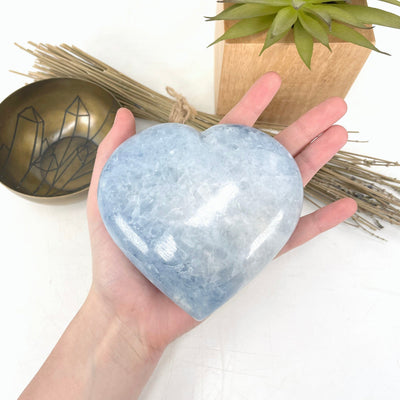 blue calcite polished heart in hand for size reference