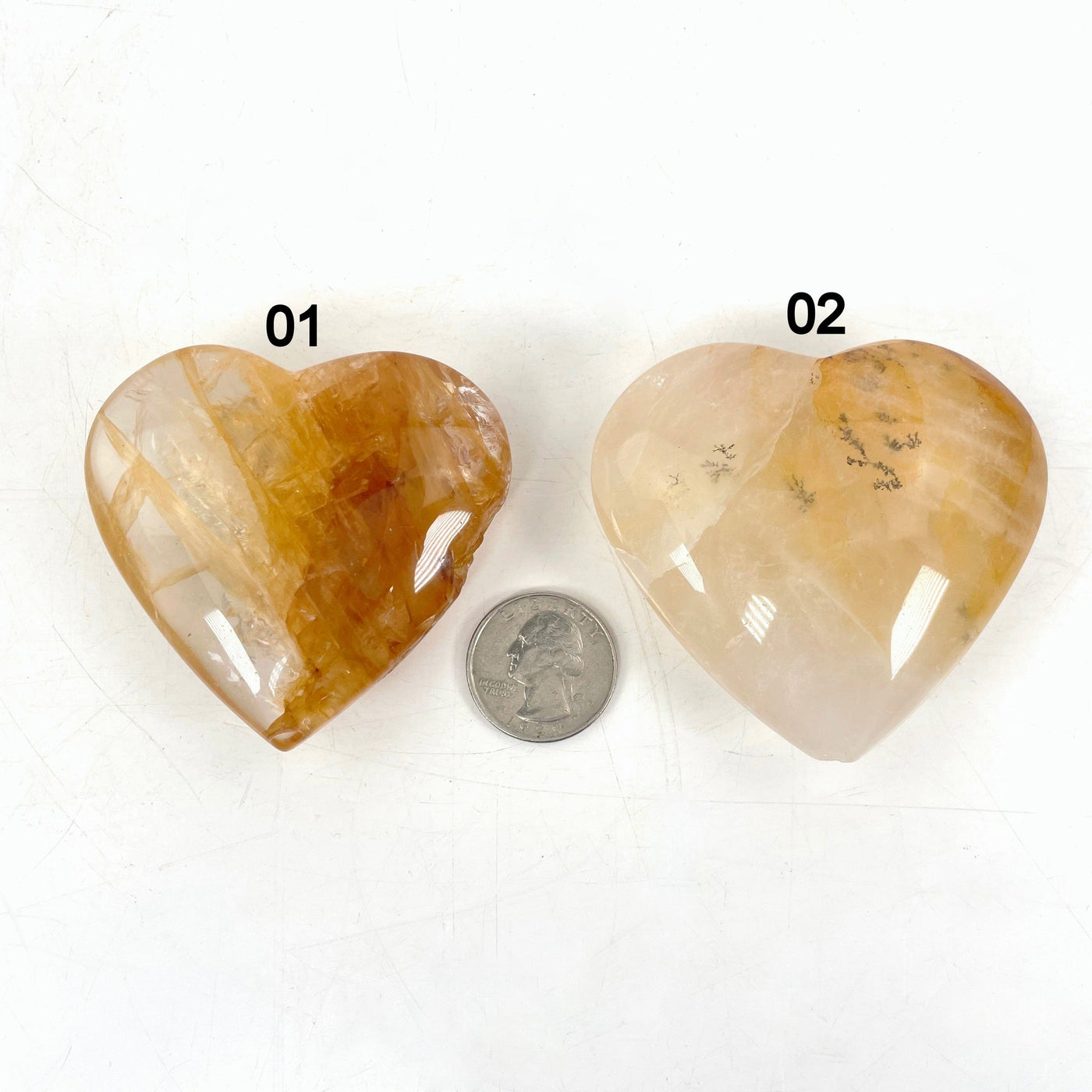 both golden healer polished heart options laying flat with quarter for size reference