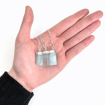 aquamarine pendant necklaces in hand for size reference