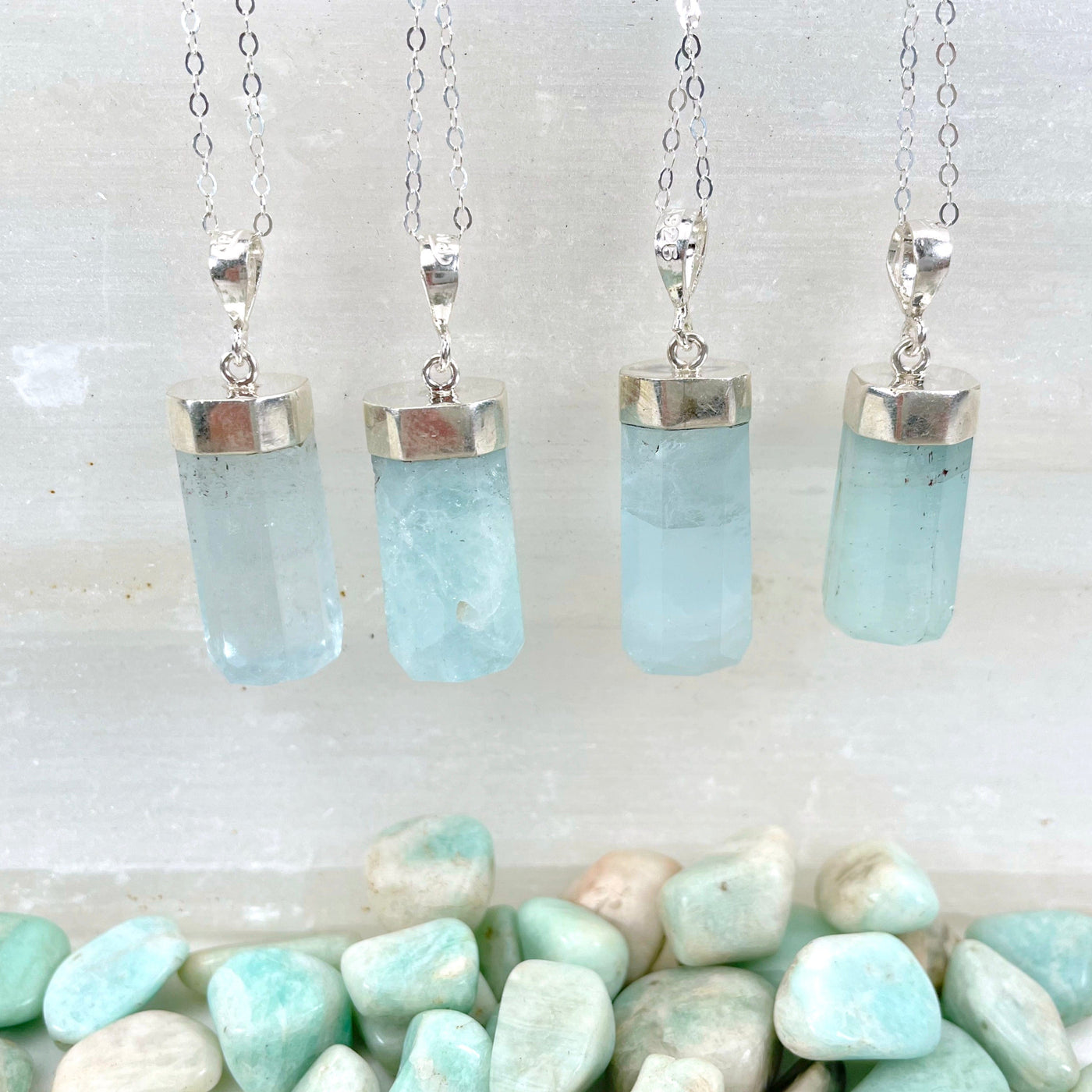 close up of aquamarine pendant necklaces hanging on display for details