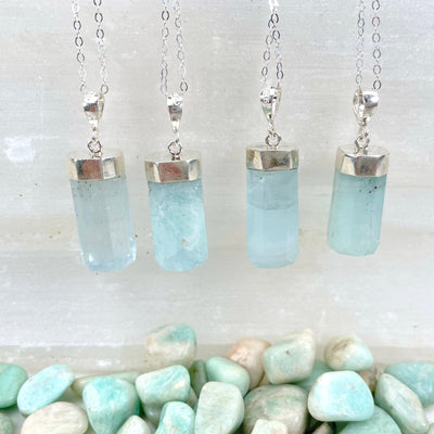close up of aquamarine pendant necklaces hanging on display for details