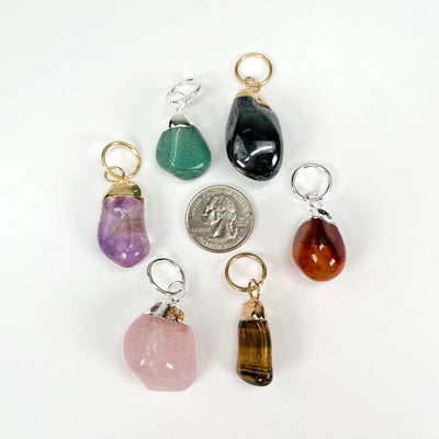 tumbled stone pendants next to a quarter for size reference 