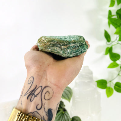 hand holding up Fuchsite Free Form showing thickness with decorations in the background