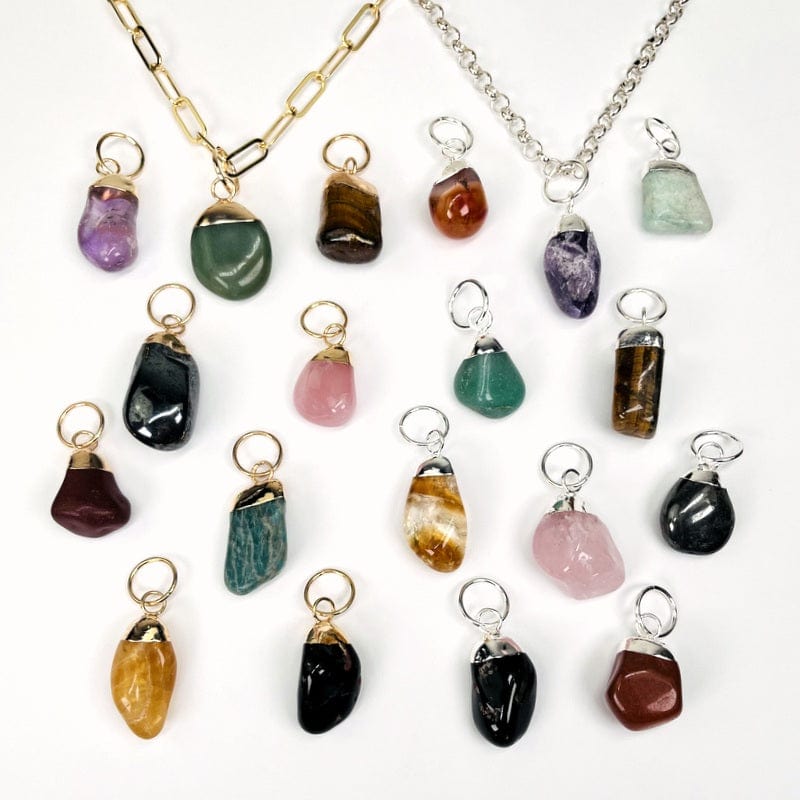 multiple tumbled stone pendants with silver and gold electroplated hoop bail pendants displayed to show the differences in the stone types 