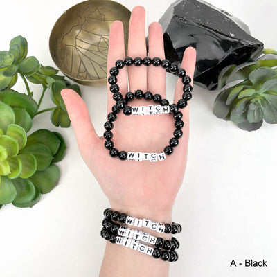 black "WITCH" letter bead option in hand and on wrist for color reference