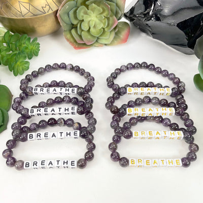 black "BREATHE" letter beads on left display and gold "BREATHE" letter beads on right display