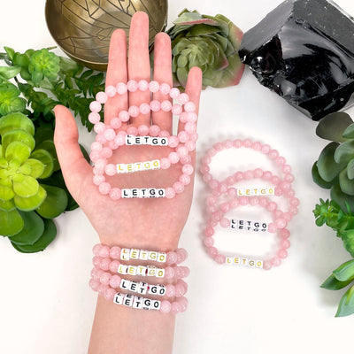 rose quartz beaded bracelet in hand and on wrist with display