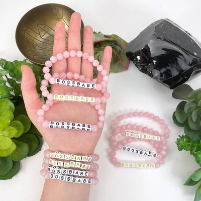 rose quartz beaded bracelets in hand and on wrist with display