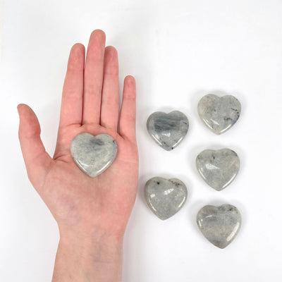 one grey moonstone polished heart in hand for size reference