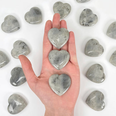grey moonstone polished hearts in hand for size reference