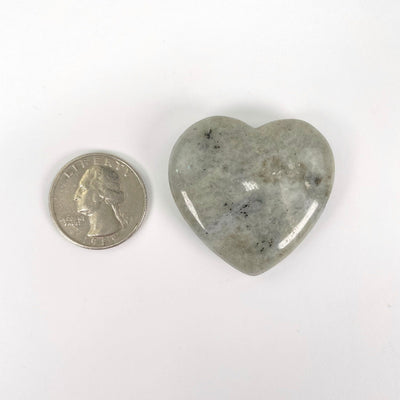 close up of grey moonstone polished heart with quarter for size reference