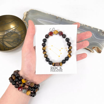 packaged leo zodiac bracelet in hand with leo zodiac bracelets on wrist