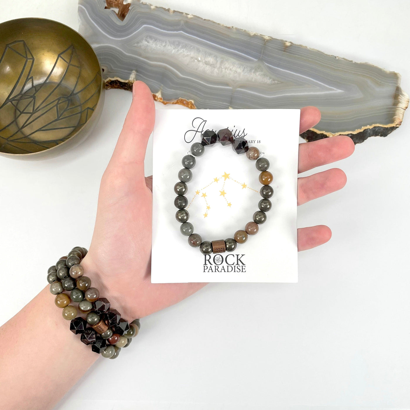 packaged aquarius zodiac bracelet in hand with aquarius zodiac bracelets on wrist