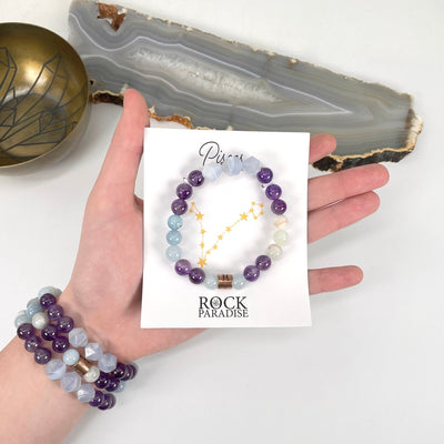 packaged pisces zodiac bracelet in hand with pisces zodiac bracelets on wrist