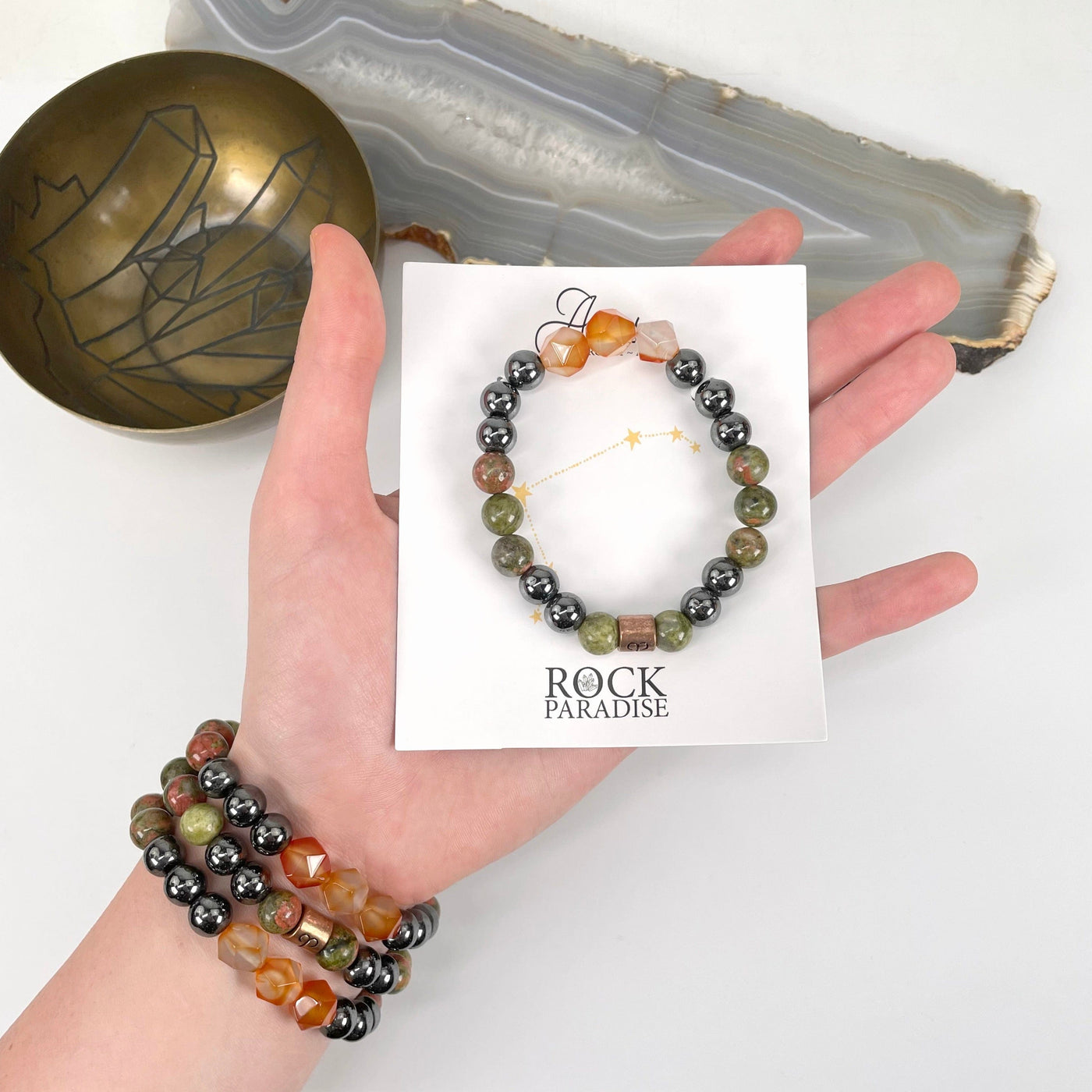 packaged aries zodiac bracelet in hand with aries zodiac bracelets on wrist