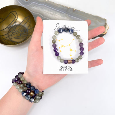 packaged sagittarius zodiac bracelet in hand with sagittarius zodiac bracelets on wrist