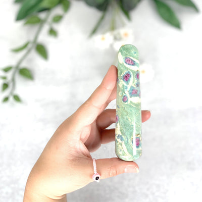 Hand showing holding the front side of the Ruby Fuchsite Massage Wand 