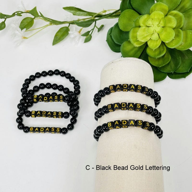 black obsidian round bead bracelet with black square beads that spell out BADASS in gold