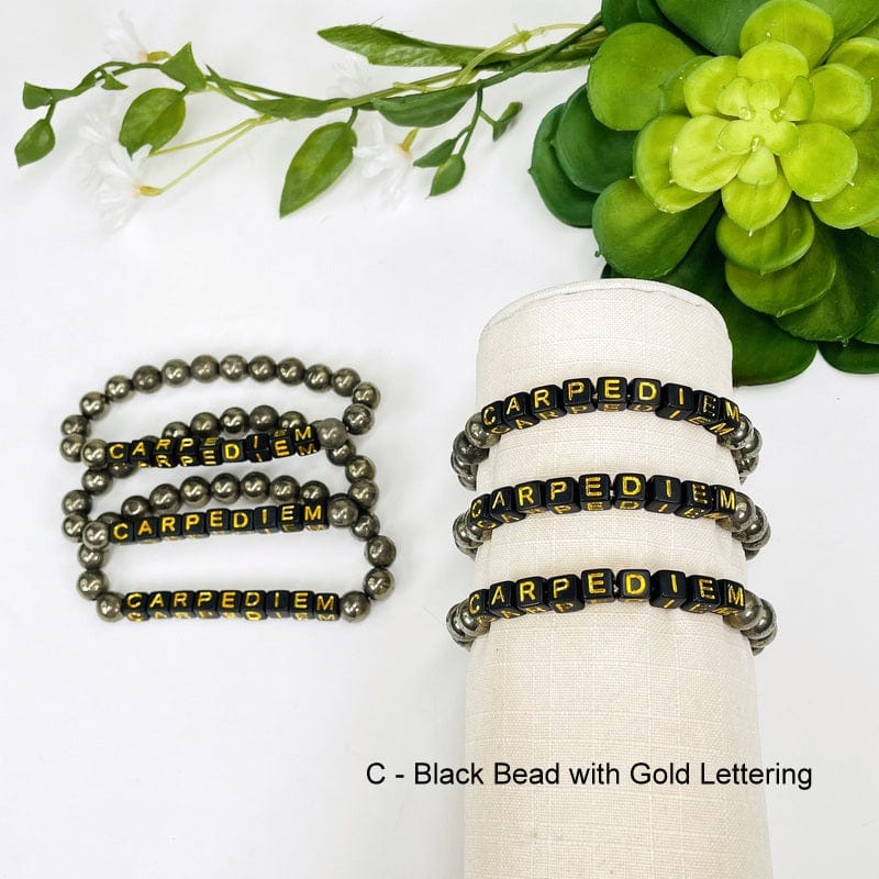 pyrite bead bracelet with black beads and gold letters spelling out CARPEDIEM 