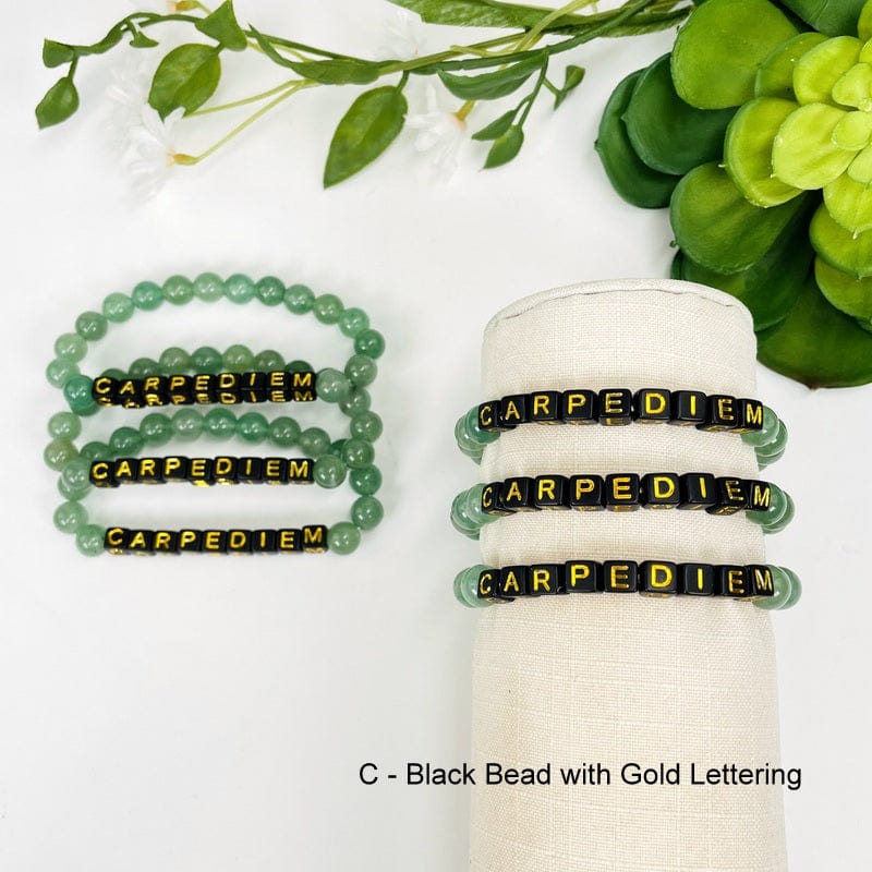 aventurine bead bracelet with black beads and gold lettering spelling out CARPEDIEM 