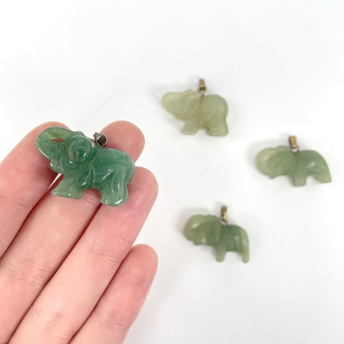 green quartz elephant pendants in hand and on display