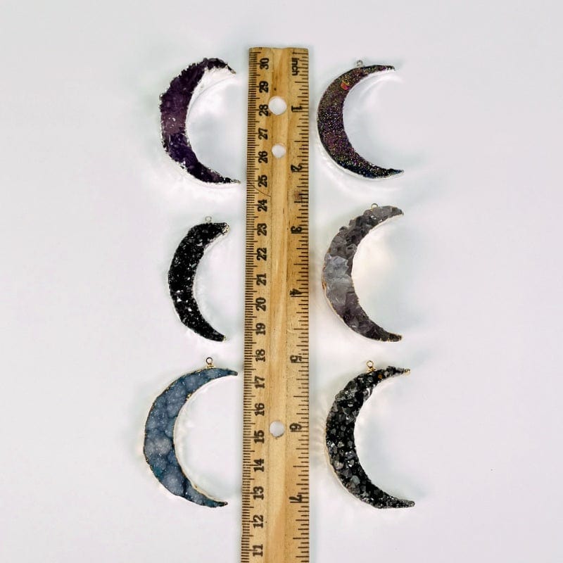  moon crescent pendants next to a ruler for size reference 