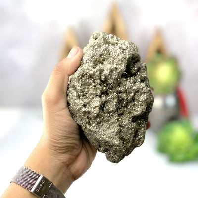 Hand holding the backside of the Pyrite Cluster