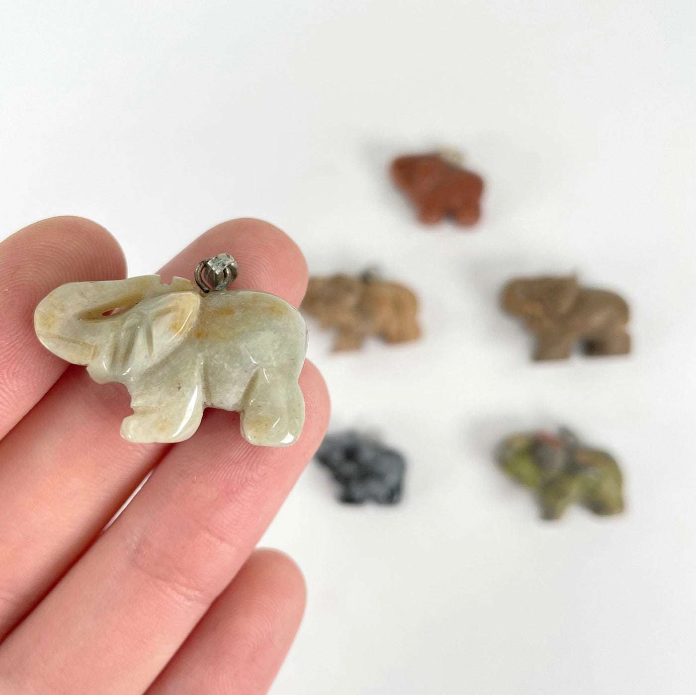 elephant pendants in hand and on display for size reference