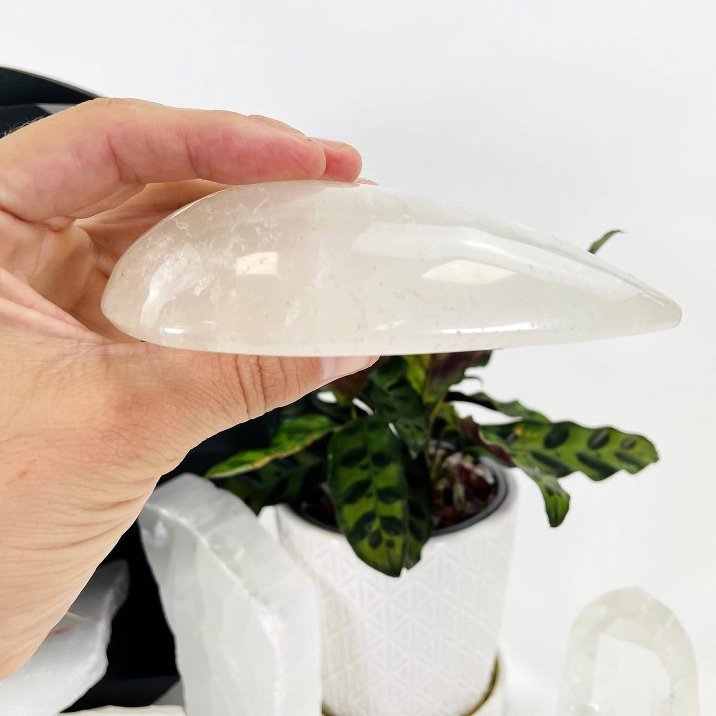 hand holding up Clear Quartz Tear Drop Shape showing side view of it