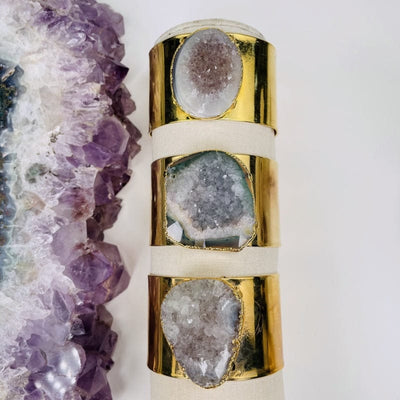 multiple amethyst cuff bracelets displayed to show the differences in the drusy 