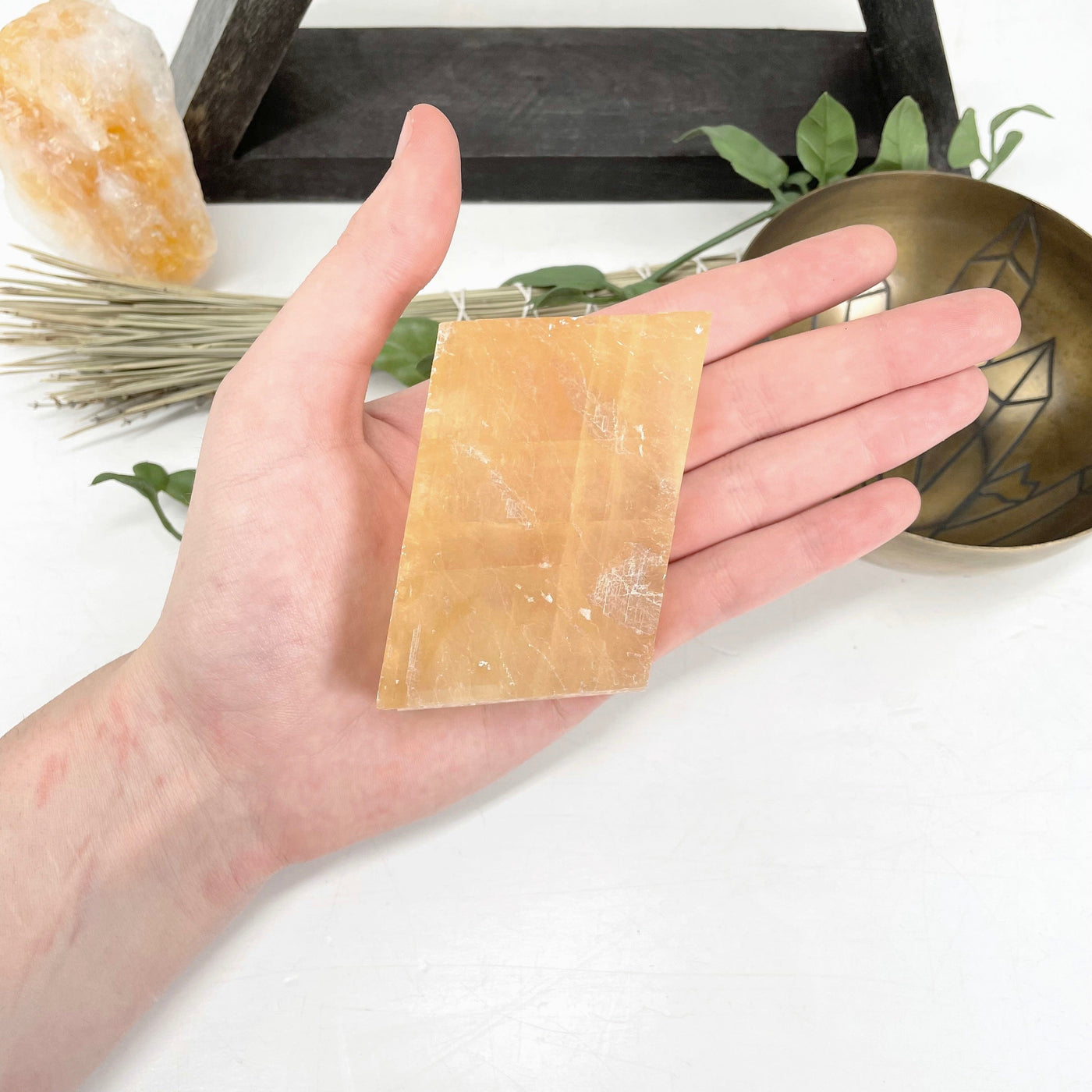 orange calcite cube in hand for size reference