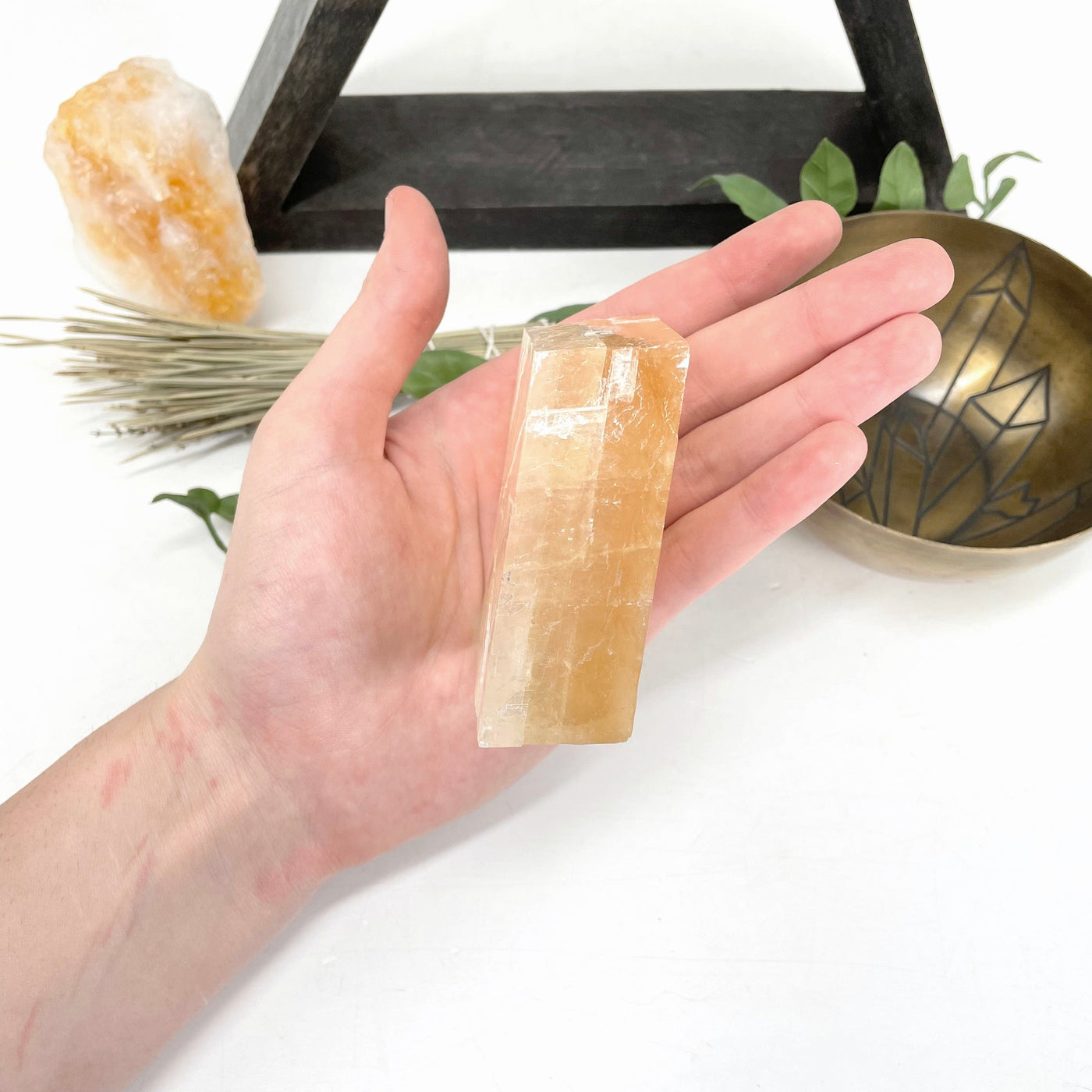 size view of orange calcite cube in hand for thickness
